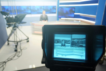 TV studio.Male silhouette of the presenter reads on a teleprompter.