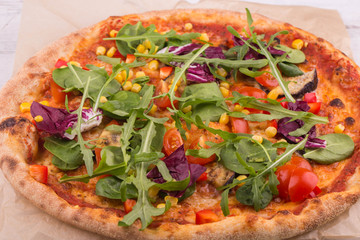 Pizza with Romano's leaves and arugula, with cherry tomatoes and corn