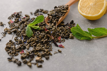 Dry green tea leaves and lemon on table