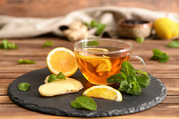 Glass cup of aromatic tea with lemon and ginger on slate plate