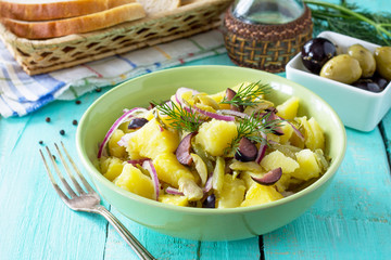 Vegetarian breakfast in a bowl of potatoes, marinated cucumbers, onions and olives on a wooden table in a rustic style. Diet, concept of vegetarian food.