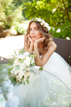 a young bride sits at a glass table with her hands folded at the chin