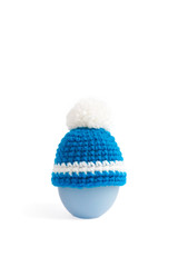 Crochet Easter Egg Hat isolated on a white background. Amigurumi of an Easter egg hat. Crochet pattern is made into blue winter knitting hat with pom pom on top