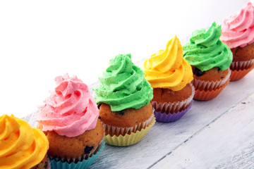 Tasty cupcakes on wooden background. Birthday cupcake in rainbow colors