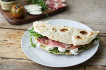 Homemade Italian flatbread called piadina with rocket salad, prosciutto and ricotta cheese.