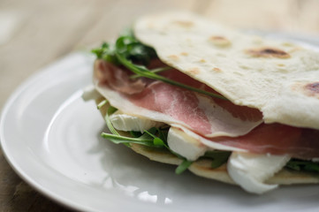Homemade Italian flatbread called piadina with rocket salad, prosciutto and ricotta cheese.