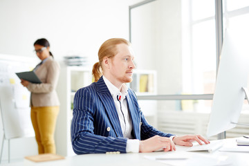 Businessman using computer at the table with woman in the background