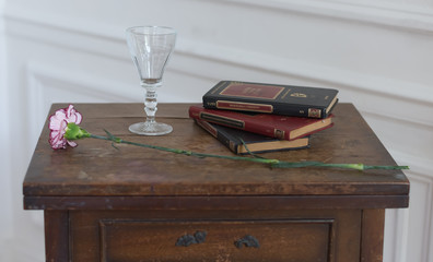 Una copa, una rosa y libros en la mesa