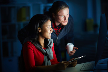 Businesspeople working in team till night. They are using computer for work