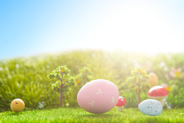 Colorful easter eggs and one big pink easter egg on spring green grass
