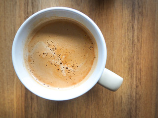 A cup of white coffee on the brown table