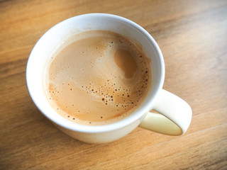A cup of white coffee on the brown table