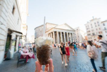 Appetizing coffee ice cream in female hand over Pantheon city view, Rome, Italy. Tasty ice cream...