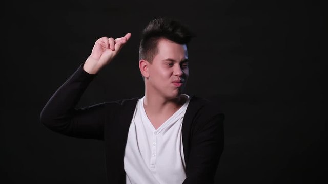 An attractive young man dancing against a black background. Medium Shot