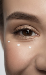 Perfect skin care concept. Close up of smiling girl eye with drops of moisturizer cream around. Selective focus