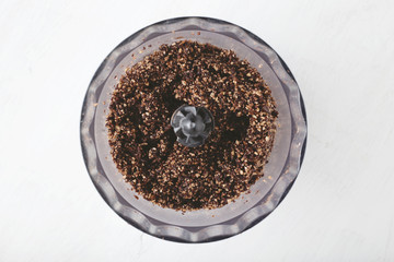 The mixture of chopped nuts, dates with cocoa powder and coconut flakes in food processor for cooking energy bites. - 196891880