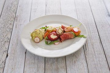 Plate of colored italian antipasti food on a wwooden table