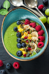 Green avocado, spinach and grape smoothie garnished with fresh fruit