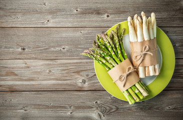 Bunches of fresh green and white asparagus on wooden background
