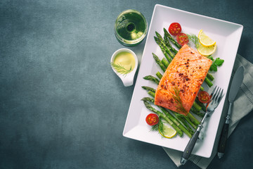 Grilled salmon garnished with green asparagus and tomatoes