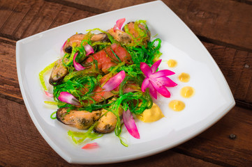Salad with salmon, seaweed and mussels. Wooden rustic background. Top view