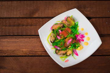 Salad with salmon, seaweed and mussels. Wooden rustic background. Top view