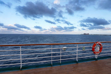 Empty wooden deck and railing with a life ring hanging on the rail on a passenger boat or cruise ship, with  ocean in a travel concept