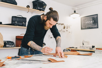 Working process in the leather workshop. Man holding crafting tool and working.