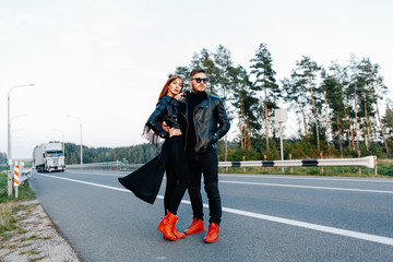 bearded guy hugs his red-haired girl on the edge of the road