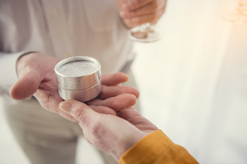 Close up of male and female wrinkled hands holding small case for ring