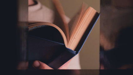 The man takes the book from the shelf and flips through it.
