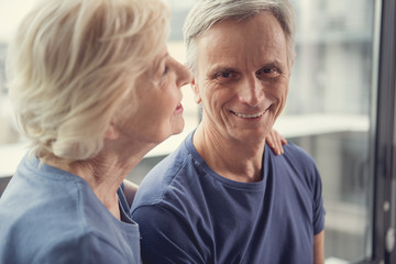 Love has no age. Glad married pensioners hugging indoors. Focus on male person