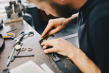 Leather craftsman working with leather. Working process in the leather workshop.
