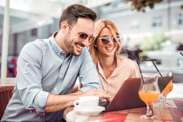Couple using laptop in cafe