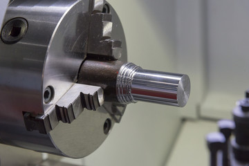 The metal rod clamped in the CNC lathe machine.
