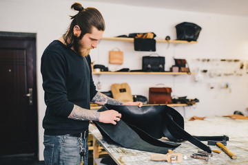 Working process of the leather bag in the leather workshop. Сrafting tool on work table background.