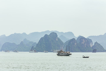 Seascape with towering limestone islands over emerald water with growing trees on it that view from cruising tourist boat in summer at Quang Ninh, Vietnam.