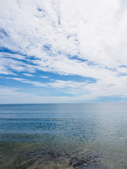 Fototapeta premium Wide angle view of calm ocean waters with a beautiful stratocumulus cloud formation on a sunny day. Hua Hin, Thailand. Travel and nature concept.