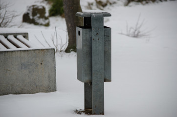 A galvanized trashcan standing in the snow