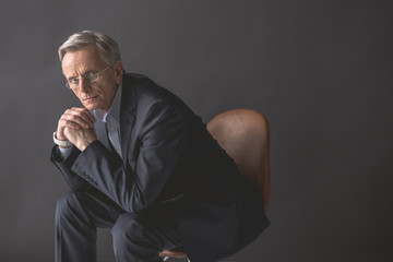 Portrait of thoughtful mature male leaning on arm while looking at camera. Demure retire worker...