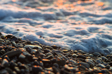 pebble stones on the sea beach, the rolling waves of the sea with foam