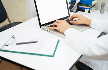 Fototapeta na wymiar Doctor hands using laptop with blank screen on desk in medical office.