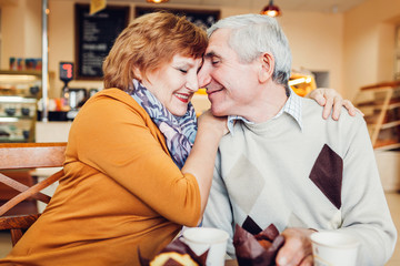 Senior couple celebrating anniversary in the cafe. Couple hugging and drinking coffee