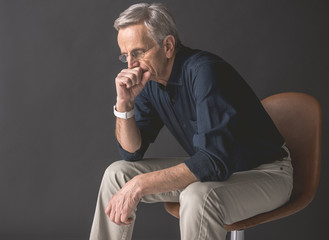 Side view calm old man thinking while closing mouth by arm. He locating on seat