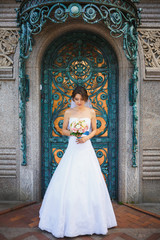 Bride in wedding dress against metal gate with bouquet