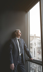 Fototapeta premium Side view pleased retire male watching at street during break at work. Relax at labor concept