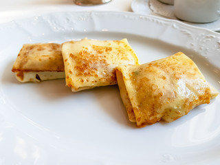 Pancakes with flesh rolled envelope lie on a white plate.
