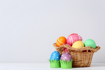 Colorful easter eggs in basket on grey background