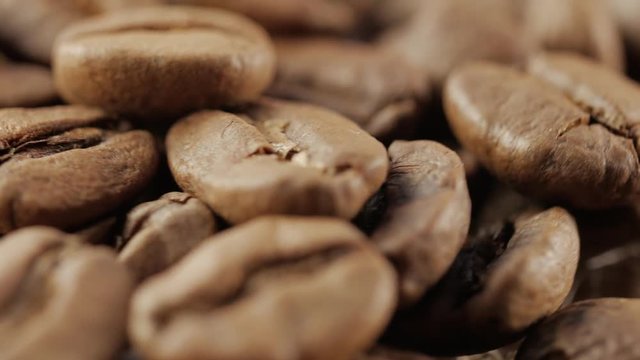 Slow rotation of the heap of coffee beans. Close up of coffee beans. Loopable rotation. In front of the camera rotates plate with coffee beans.