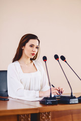 girl at the table speaks in microphones at conference hall